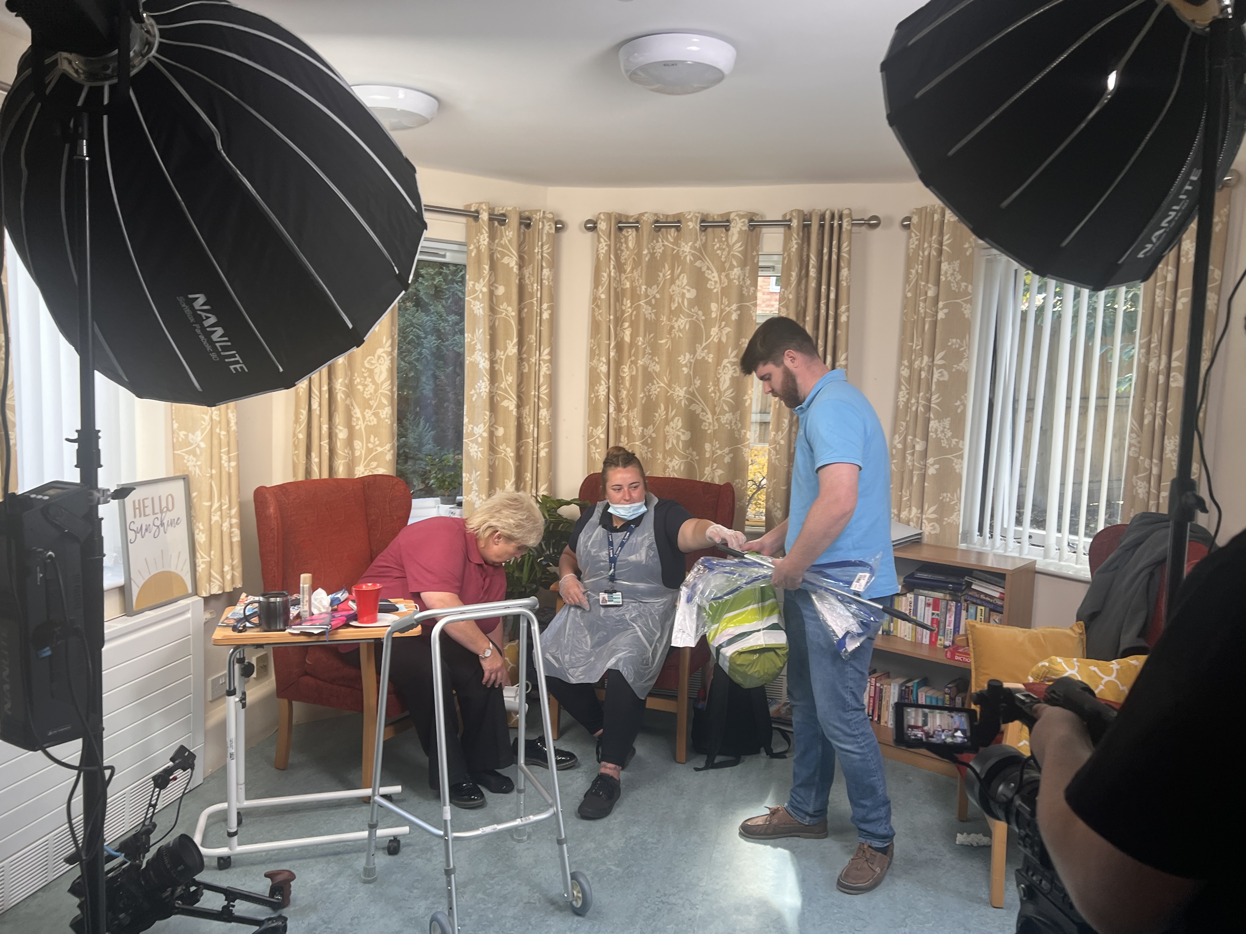 A film set, with lights, actors and an assistant monitoring the production. 